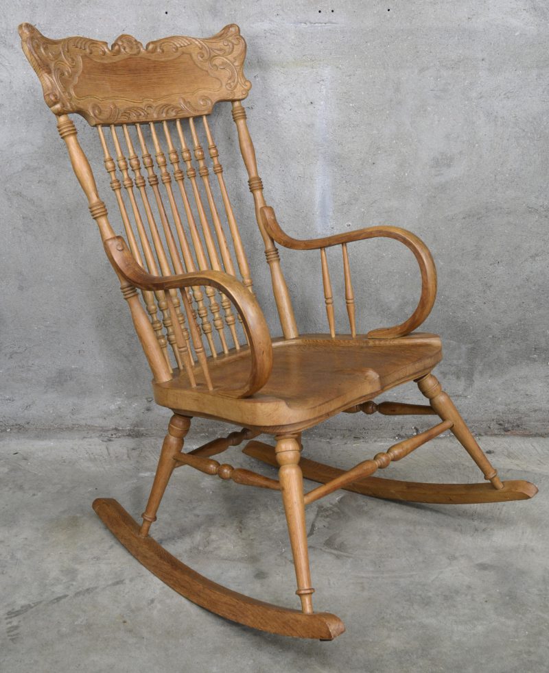 Een massief eikenhouten schommelstoel met gesculpteerde delen.