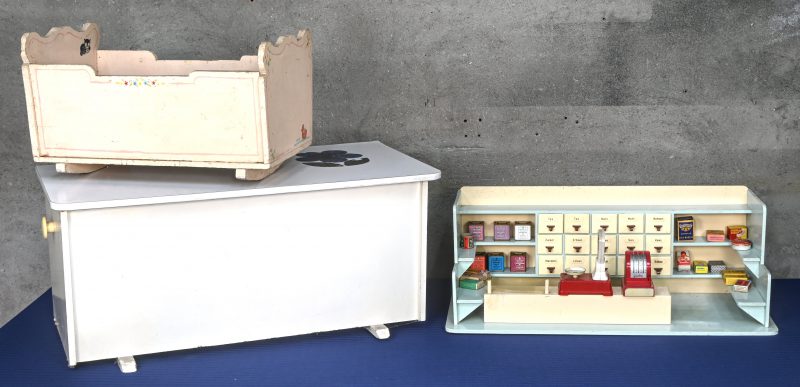 Een lot vintage speelgoed bestaande uit een koffer, een poppenbedje en een winkeltje met vele toebehoren.