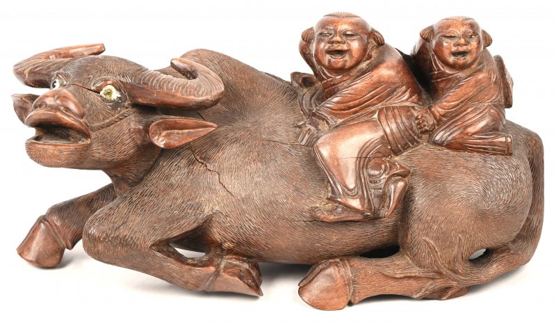 Houten beeldje van een waterbuffel met twee kinderen op de rug. Aziatisch houtsnijwerk. 1 oog is hersteld, er loopt een barstje door het hoofd en de flank.