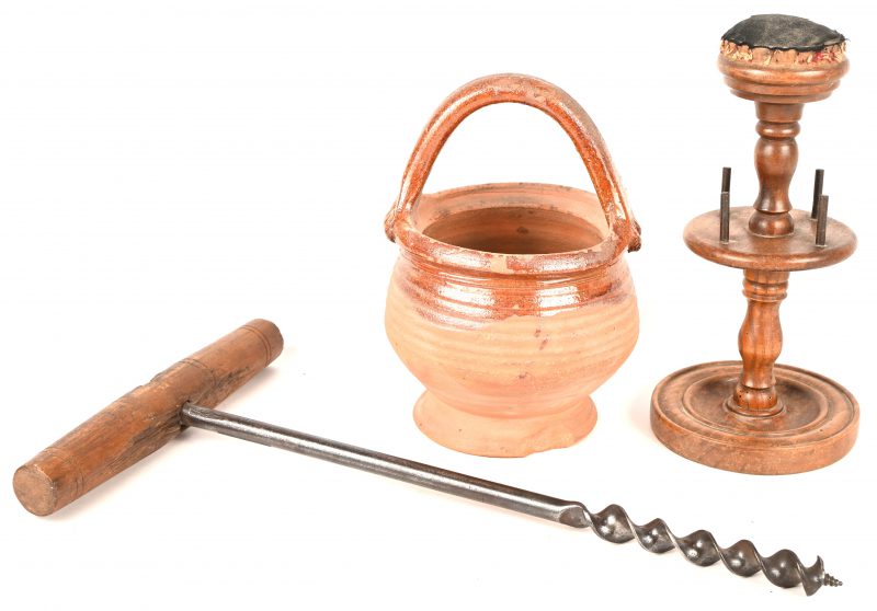 Een gevarieerd lot bestaande uit een antieke houtboor voor balken, een spoelhouder met speldenkussen en een terracotta pot met oor.