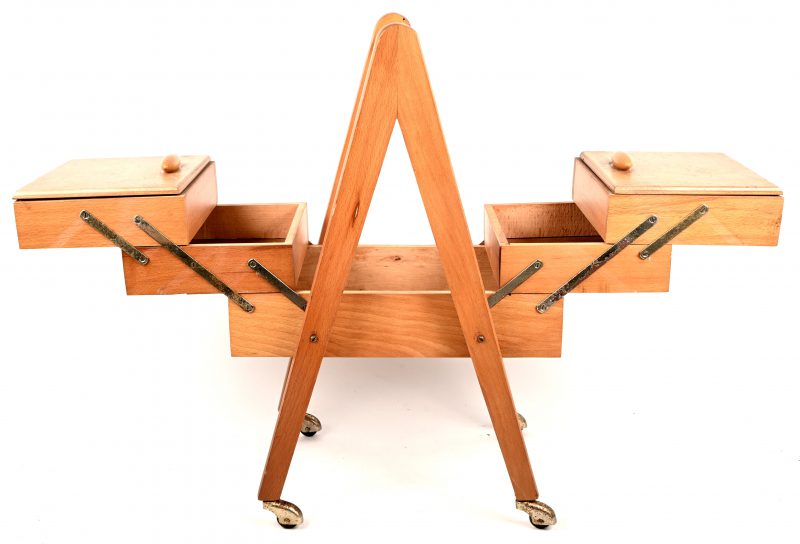 Een houten vintage naaidoos op wieltjes.