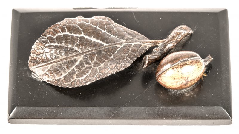 Art-deco bureaudecoratie bestaande uit een marmeren sokkeltje met een bronzen blad en noot. Niet gesigneerd.