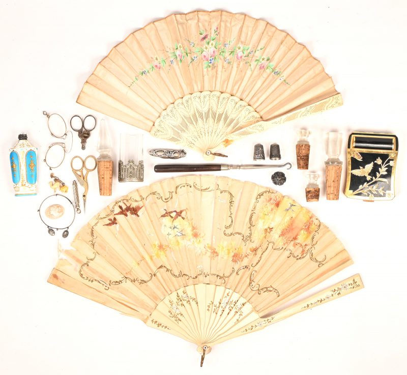 Een gevarieerd lot bestaande uit 2 antieke waaiers, een pocket make-up set,   borrelglaasje, porseleinen parfumflesje, knopenhaak, 2 vingerhoeden, armbandje, schaartje, sigarenknipper, zakmesje, pince-nez, camée, naaldenkokertje, bedeltjes en 4 kristallen/kurkenstoppen.