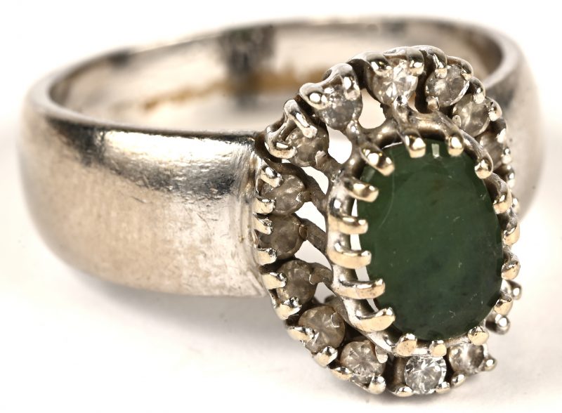 Een 18 kt witgouden ring bezet met een centrale smaragd van +- 1 ct. en fantasiestentjes.