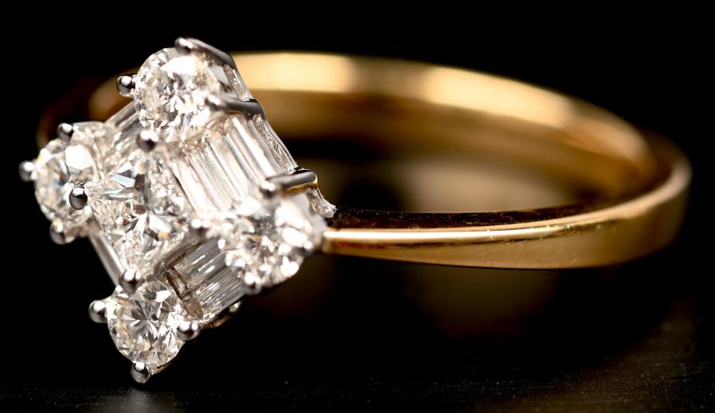 Een 18 kt wit- en geelgouden ring bezet met briljanten en baguetten met een gezamenlijk gewicht van 0,72 ct.