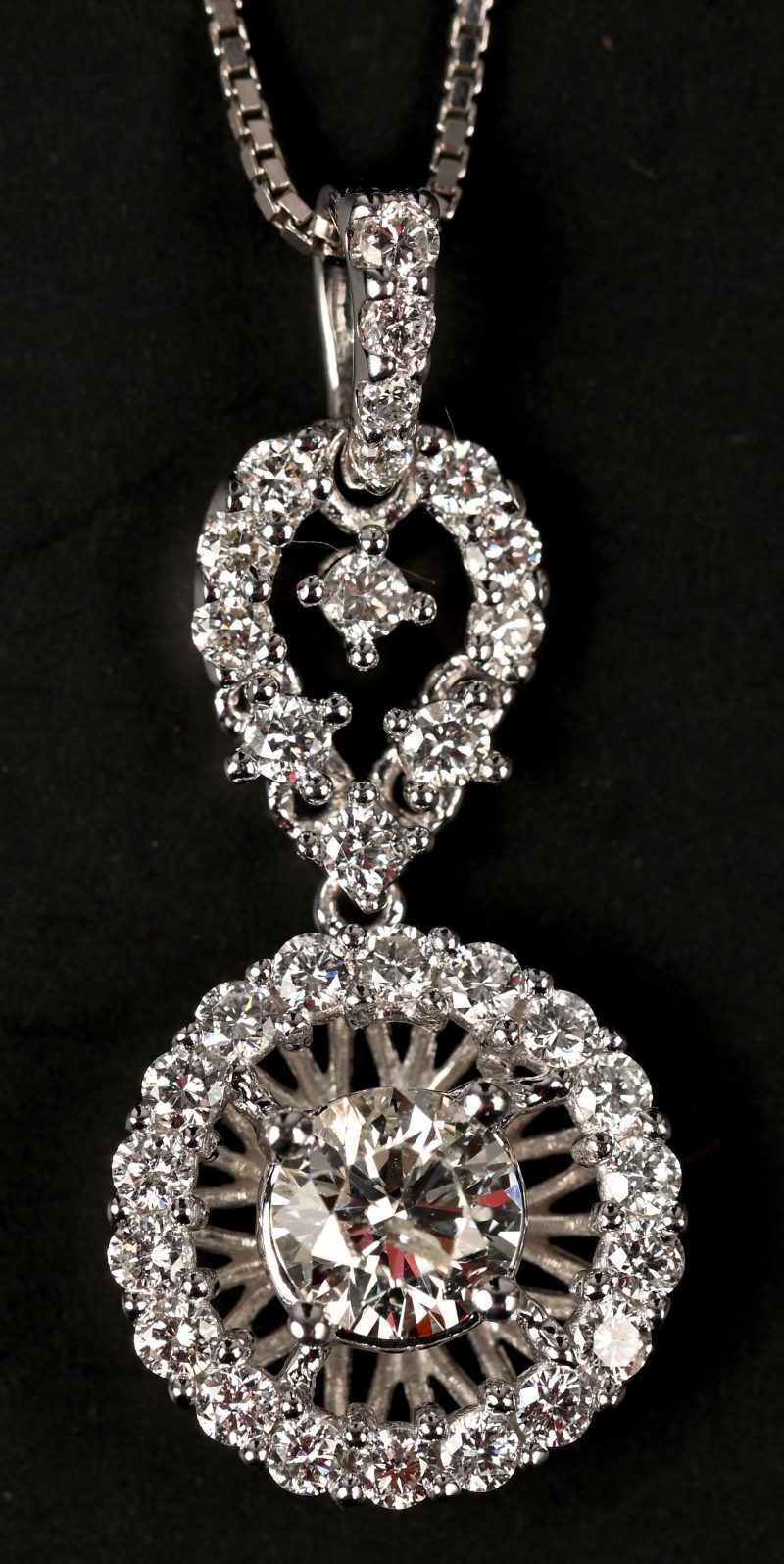 Een 18 kt witgouden ketting met hanger met een centrale briljant van 0,35 ct, en briljanten met een gezamenlijk gewicht van 0,39 ct.