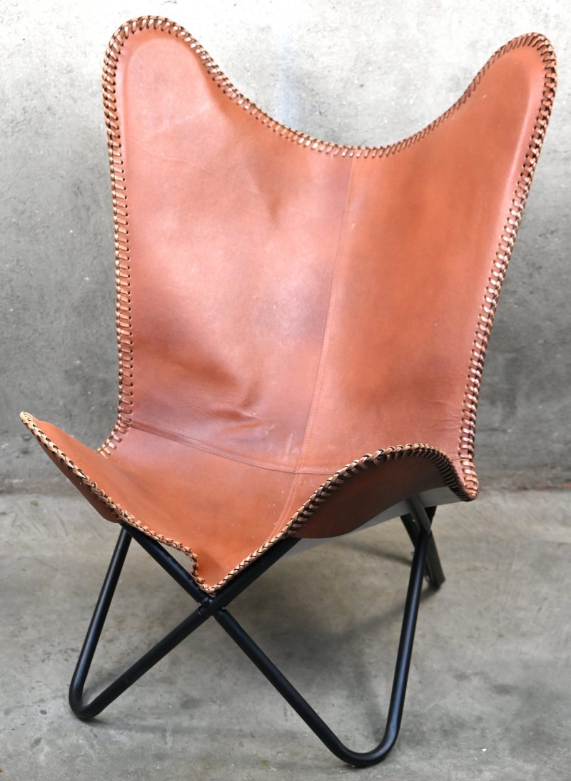 Een bruinlederen vlinderstoel op metalen buisframe. In vintage stijl.