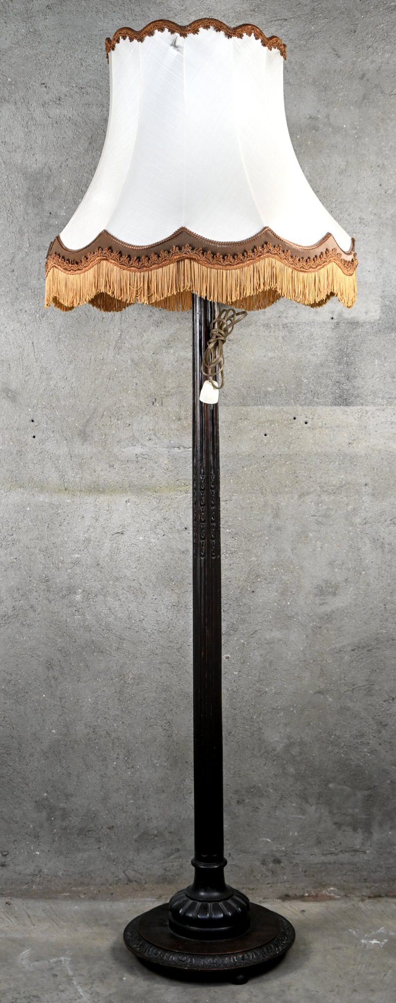 Een staande lamp met massief houten gesculpteerde voet.