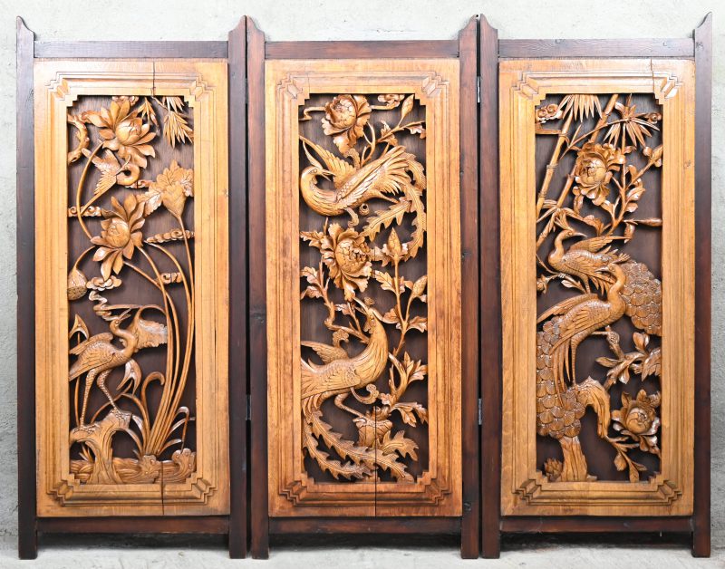Een laag kamerscherm bestaande uit drie gesculpteerde panelen met  vogels, bamboe en bloemen.