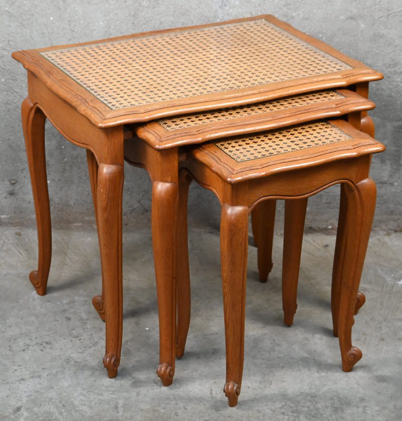 Een set van drie houten bijzettafeltjes in rustieke stijl. Met glazen bladen op cannage.