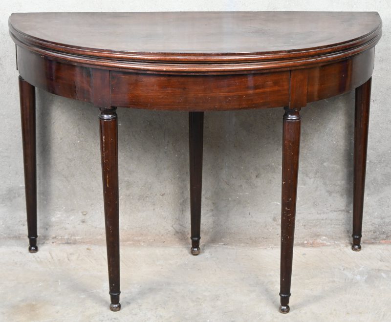 Een halfronde muurtafel, openklapbaar tot kaarttafel. Met verborgen lade in de extra poot. Met een beetje schade aan het kaartblad.