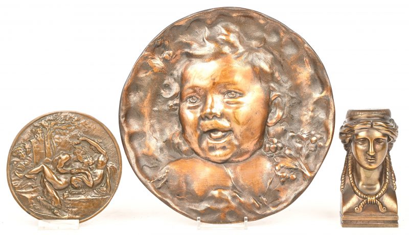 Drie stuks brons, een plaquette met een kinderhoofdje, een plaquette met een erotische scène en een Minervahoofdje.