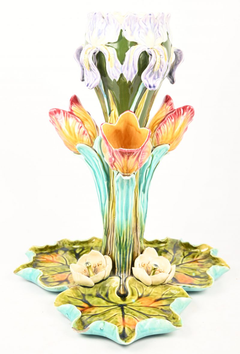 Een halfhoge Barbotine vaas, gevormd als tulpen en irissen op een basis van waterlelies. Met schilferschade aan de basis.