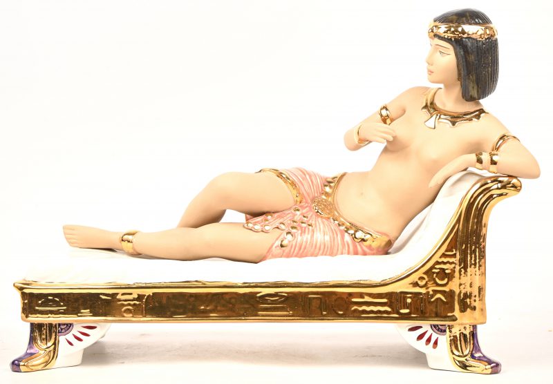 Een porseleinen beeld voorstellend een Egyptische dame op chaise longue.