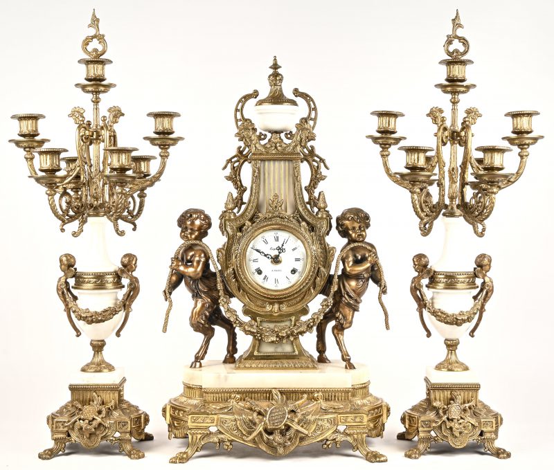 Een 3-delige pendule in brons, marmer en messing, Regnault à Paris, gedragen door 2 faunen, met 2 bijhorende kandelaarsvoor 7 kaarsen elks.
