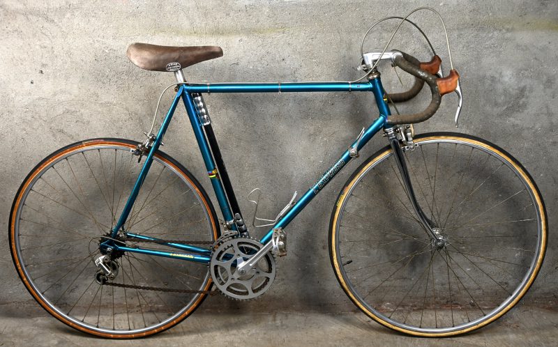 Een blauwe vintage stalen koersfiets van het Belgische merk L’EXPRESS, framemaat 60.