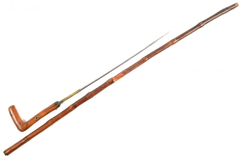 Een antieke houten wandelstok met een verborgen dolk. Het lemmet heeft een lengte van 35 cm en is geëtst. Het hout vertoont enkele barsten en een paar stukken van het beslag zijn manco.