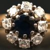Een 18 kt wit en geelgouden ring bezet met een centrale saffier van +- 0,25 ct. en diamanten met een gezamenlijk gewicht van +- 0,40 ct.