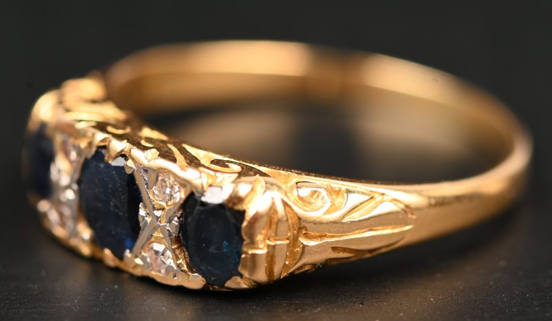 Een 18 kt wit en geelgouden ring bezet vier diamanten oude slijp en drie saffieren met een gezamenlijk gewicht van +- 0,50 ct.