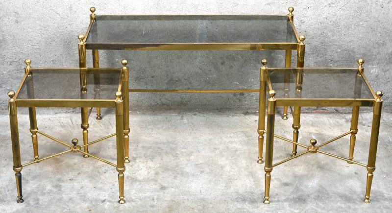 Een set van drie messing bijzettafeltjes met fumee glazen blad. In goede vintage staat.