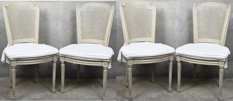 Een set van vier eetkamerstoelen met cannage zit en rug, stijl Louis XVI. Lichtgrijs gepatineerd, met bijpassende kussens.