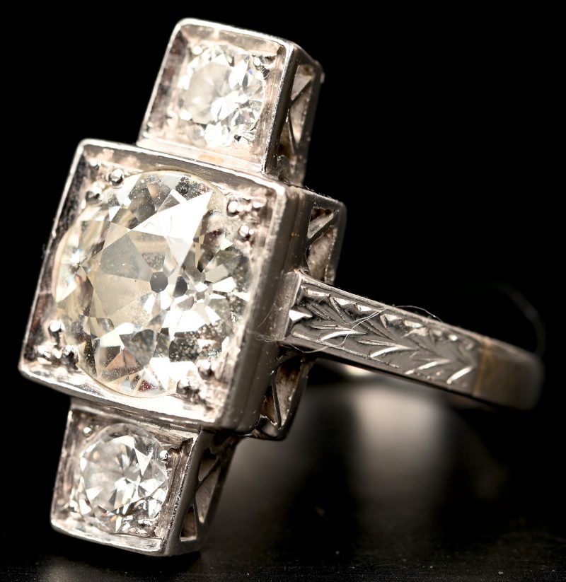 Een 18 kt witgouden ring bezet met centrale diamant van +- 2,10 ct. en twee diamanten met een gezamenlijk gewicht van +- 0,40 ct.