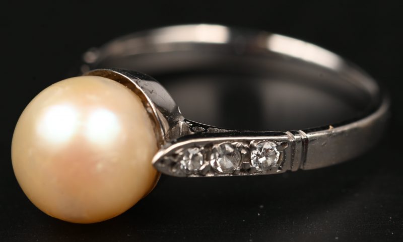 Een 18 kt witgouden ring bezet met diamanten met een gezamenlijk gewicht van +- 0,12 ct. en een parel.