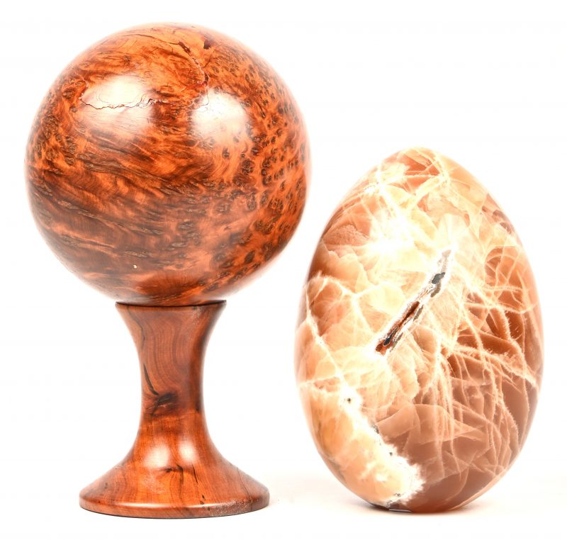 Een lot van twee decoratievoorwerpen, bestaande uit een wortelhouten bal op een voetje en een marmeren ei.