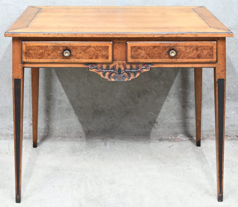 Een klassiek bijzettafeltje met twee laden. De laden zijn ingelegd met wortelfineer en het front heeft een ornamentje in relief.