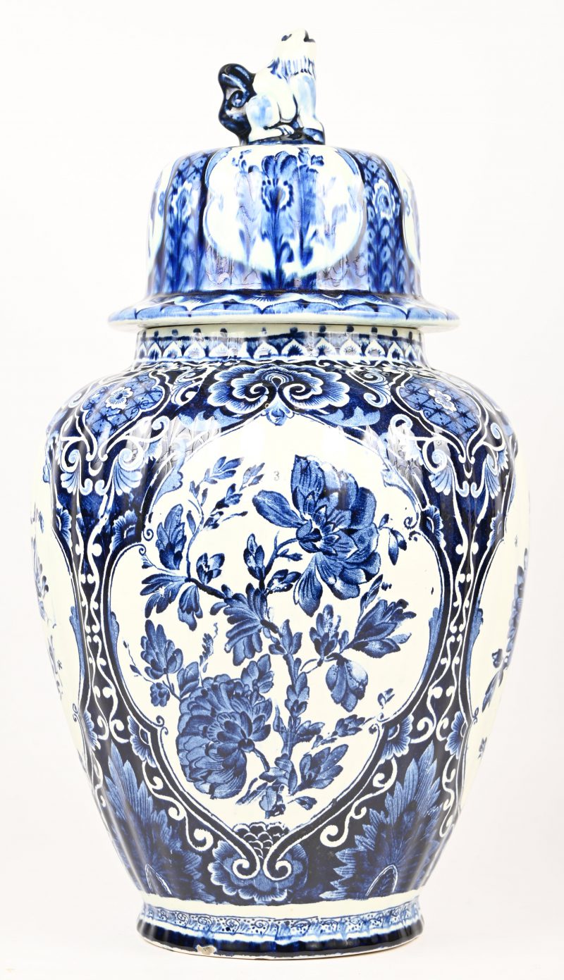 Een dekselvaas van blauw-wit gelazuurd porselein, met Delfts decor. Boch voor Royal Sphinx. Onderaan gemerkt; 2eme Choix, met grote bakfout.