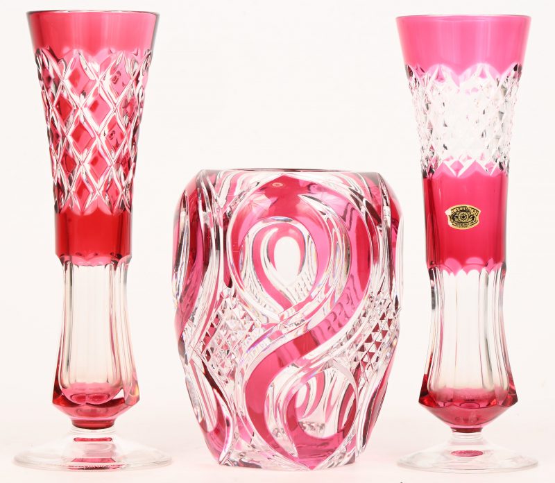 Een lot van drie vaasjes van VSL kristal. Roze in de massa gekleurd. Twee vazen zijn getekend, de derde draagt een zelfklever.