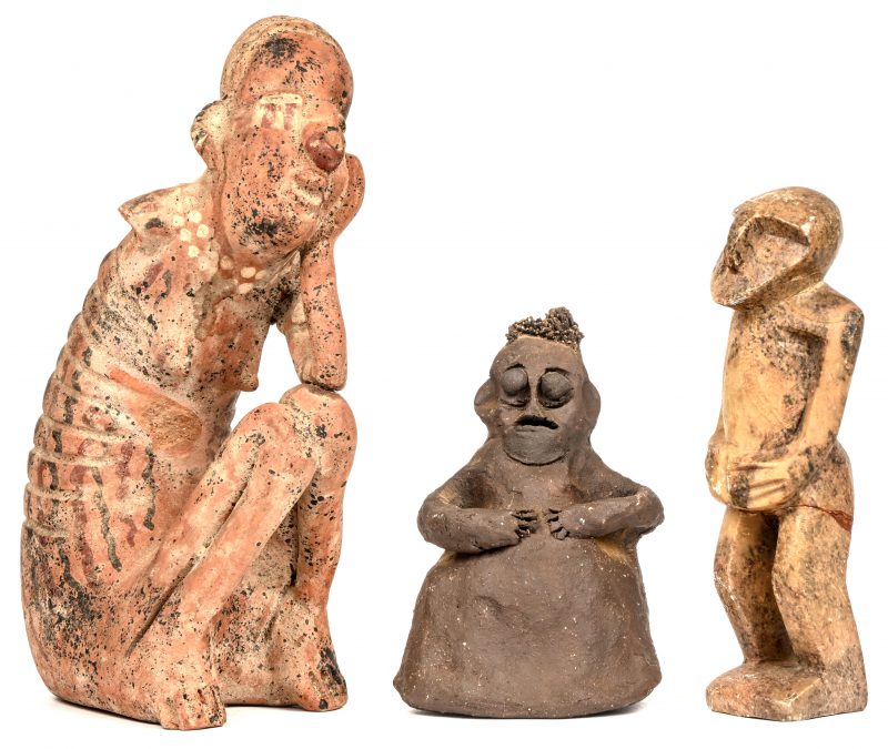 Drie etnische beeldjes. Een hurkend meisje van terracotta (een arm ontbreekt), een staande figuur van natuursteen en een figuurtje met metalen kroeshaar.