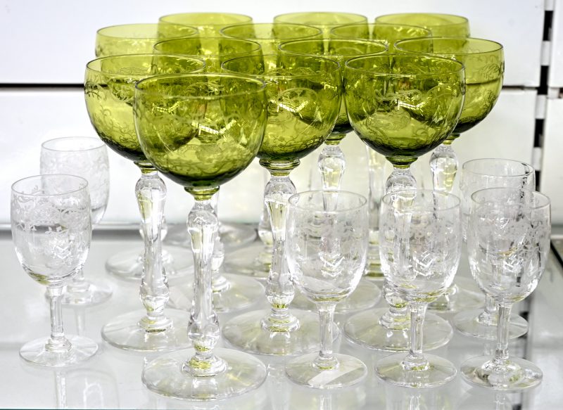 Een set van 13 kristallen wijnglazen met een groene kelk en 6 kleurloze borreltjes. Gegraveerd met een decor van bloemen en vogels.