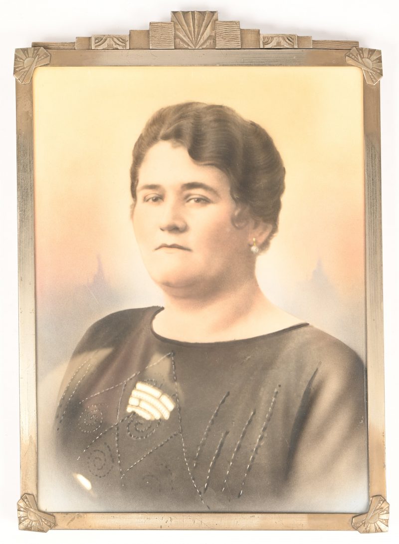 Een metalen art deco kader met een ingekleurde portret foto van een dame.