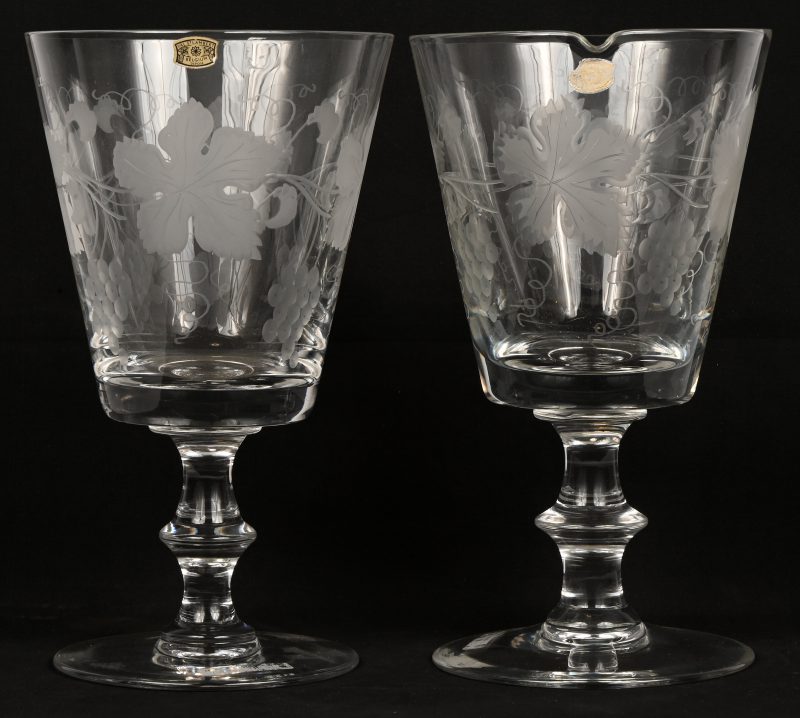 Een set van twee grote kelken van kleurloos kristal met een gegraveerd decor van wijnbladeren. Gemerkt met sticker, één kelk is getekend.