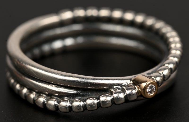 Een zilveren ring 925 ‰ bezet met één briljantje in goud gezet.