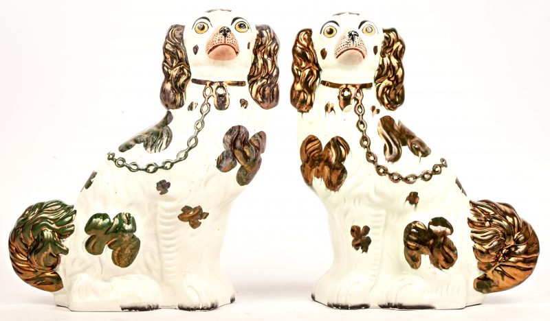 Een set meerkleurig geglazuurd aardewerken Staffordshire dogs waarvan één met schilfer.