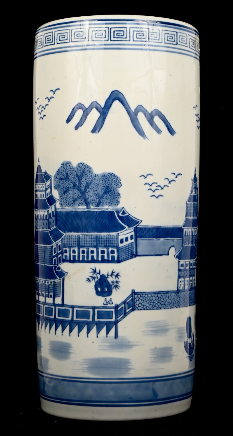 Een grote Chinees cilindervaas met blauw op wit decor van een paleis aan het water.