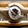 Een 18 kt wit en geelgouden ring bezet met een centrale briljant van +- 0,20 ct. en baguetten met een gezamenlijk gewicht van +- 0,20 ct.