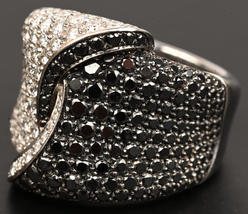 Een 18 kt witgouden ring bezet met witte briljanten met een gezamenlijk gewicht van +- 1,90 ct. GSI 1 en zwarte diamanten met een gezamenlijk gewicht van +- 2,26 ct. Met certificaat.