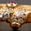18 karaats geelgouden ring bezet met briljanten met een gezamenlijk gewicht van+- 0,20 ct. en twee robijn cabochons van +- 0,20 ct.