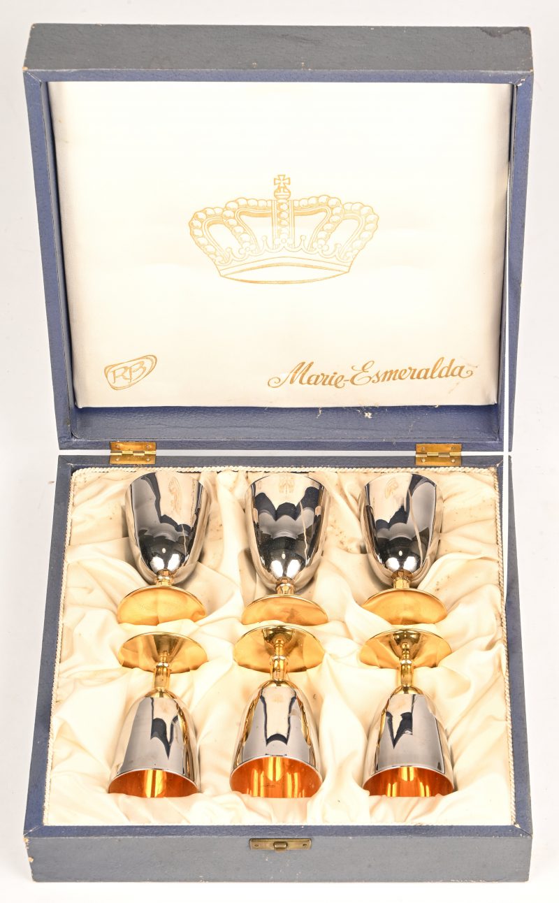 Een set van zes goud en zilverkleurige borrelglaasjes in een kistje. Draagt binnenin een afbeelding van een kroon en de naam; Marie-Esmeralda.