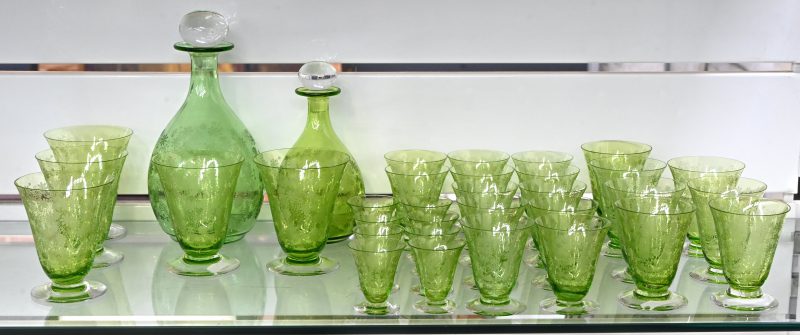 Een set van twee groenglazen karaffen en 32 glazen in drie formaten. Met een geëtst decor van bloemen, twee glazen hebben minieme schilferschade.