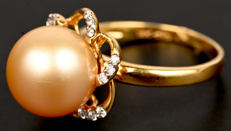 Een 18 kt geelgouden ring bezet met briljanten met centrale parel en briljanten met een gezamenlijk gewicht van 0,20 ct.