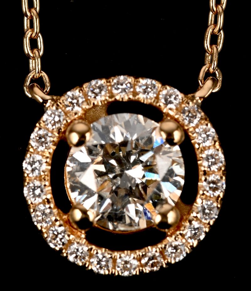Een 18 kt geelgouden ketting met hanger met een centrale briljant 0,70 ct FSI2, en briljanten met een gezamenlijk gewicht van 0,16 ct. FVS1.