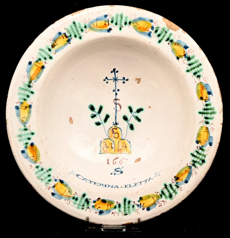 Een kommetje van meerkleurig geglazuurd aardewerk. Met religieuze symbolen en de vermelding van het jaartal 1667.