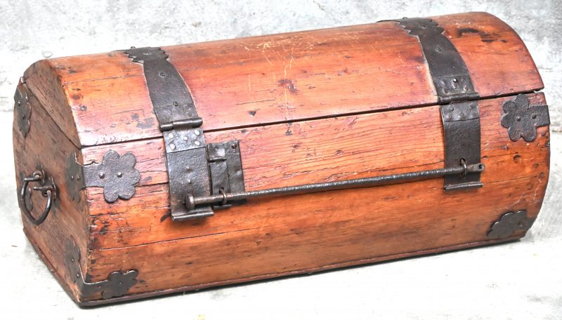 Een antieke cilindervirmige houten koffer met smeedijzeren beslag.