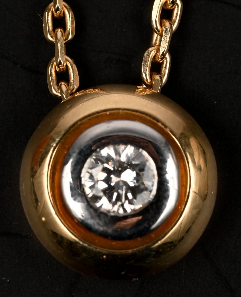 Een 18 kt geelgouden ketting met hanger van 18 kt wit en geelgoud bezet met één briljant van +- 0,20 ct.