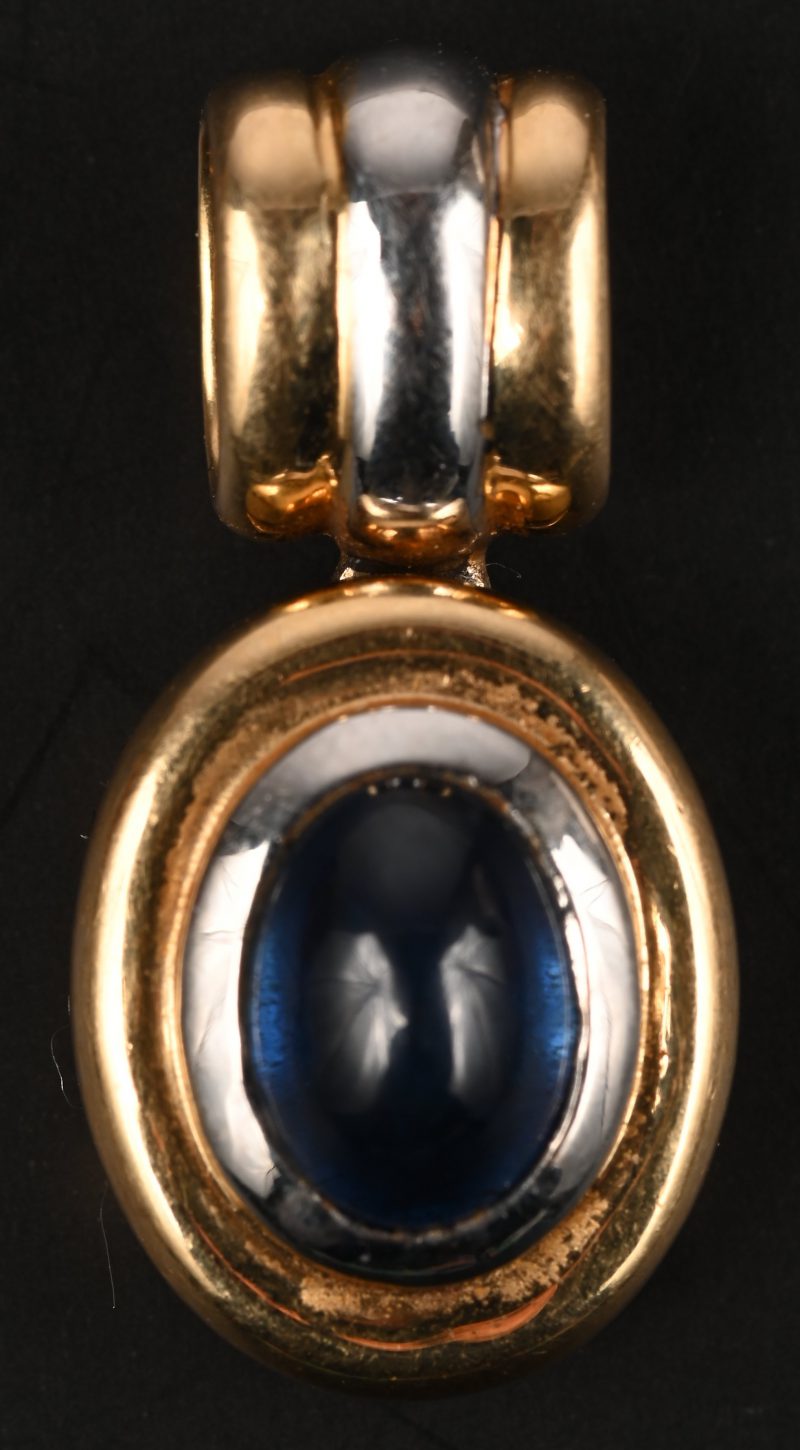Een 18 kt wit en geelgouden hanger bezet met een saffier cabochon van +- 0,50 ct.