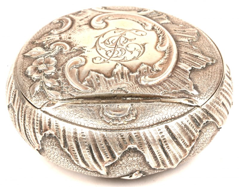 Een rijkelijk gedecoreerde zilveren poederdoos met initialen D S. 75 gram.